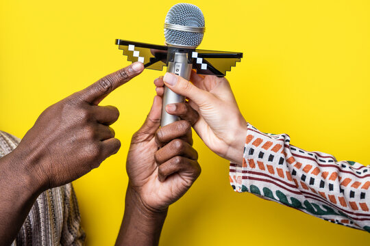 Multiethnic hands holding microphone with pixel sunglasses