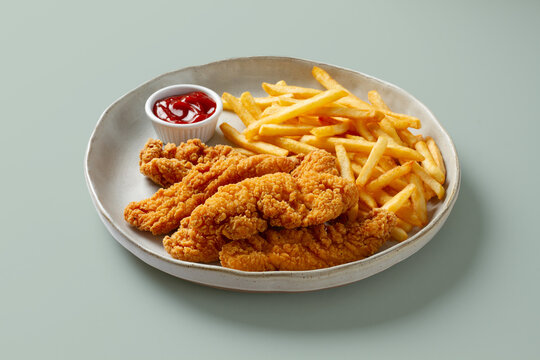 Crispy chicken tender with fries and ketchup on plate