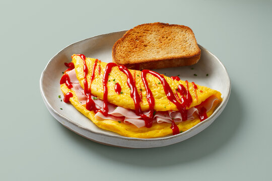 Ham omelette with toast and ketchup on ceramic plate