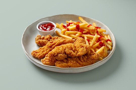 Crispy chicken tenders with fries and ketchup on plate