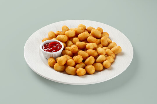 Golden tater tots with ketchup on white plate