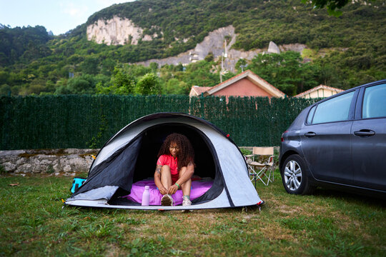 Woman tying shoelaces inside camping tent