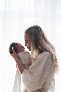 Mother holding newborn baby during first days at home