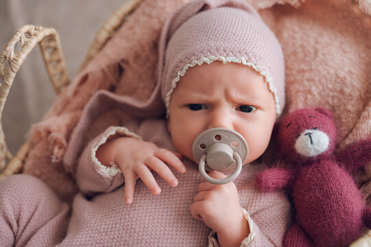 Newborn baby with pacifier and teddy bear at home