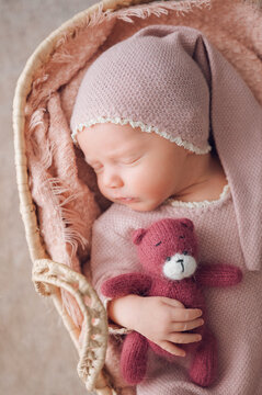 Sleeping newborn baby cuddling teddy bear in basket
