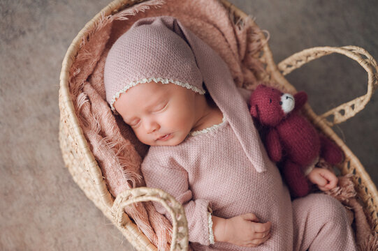 Sleeping newborn baby in basket with teddy bear