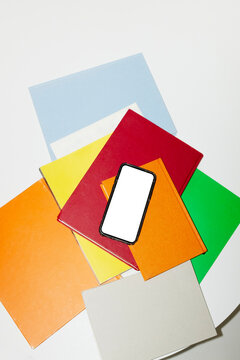 Smartphone mockup in table with colourful books and magazines
