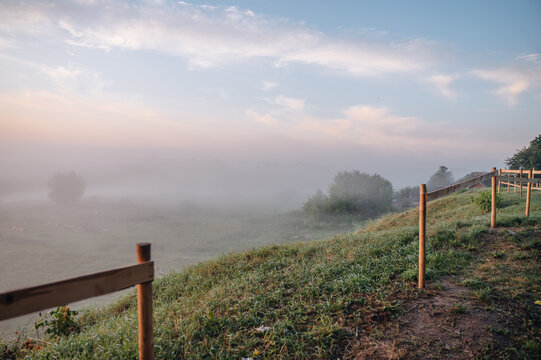 Sunrise over misty riverbank in summer countryside