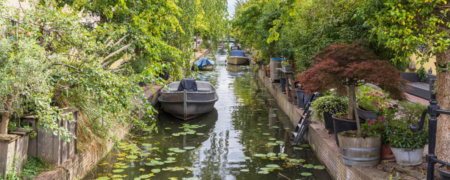 Canal boats and lush garden terraces along a narrow residential waterway in Leiden, The Netherlands