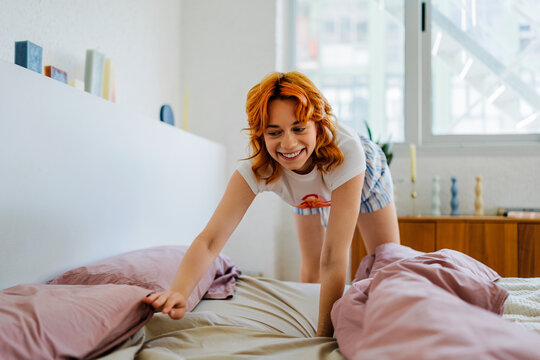 Woman making bed in a bright bedroom