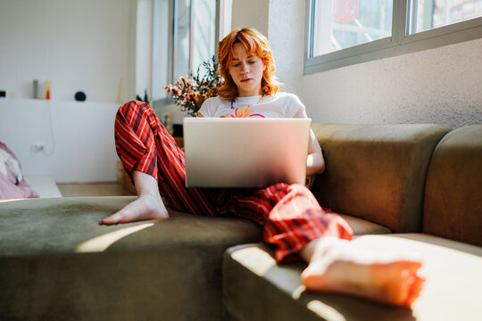 Woman working from home using laptop on sofa
