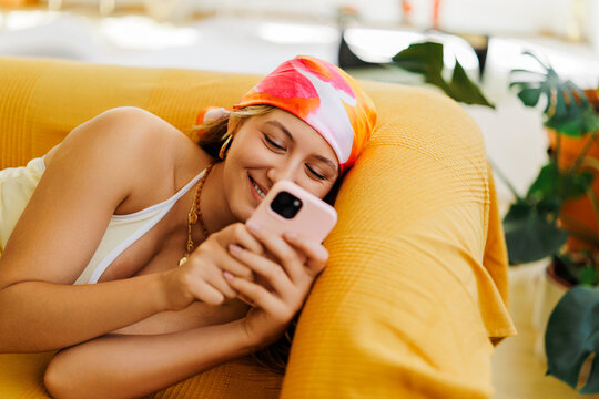 Woman smiling connecting with smartphone on couch