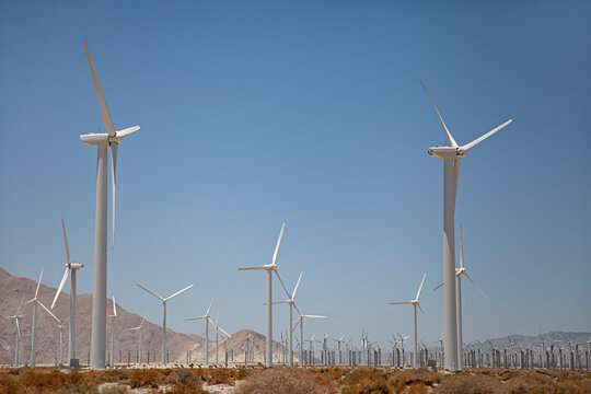 Expansive wind farm with numerous turbines under a clear blue sky