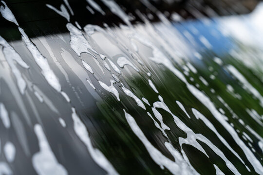 Soap foam on car windshield during outdoor car wash