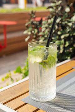 Refreshing lime drink in glass with black straw outdoors