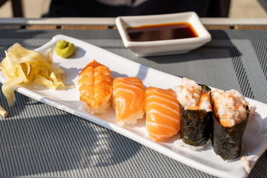 Assorted sushi pieces on white plates in a restaurant