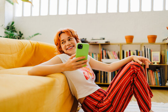 A woman smiling looking at smartphone in cozy home