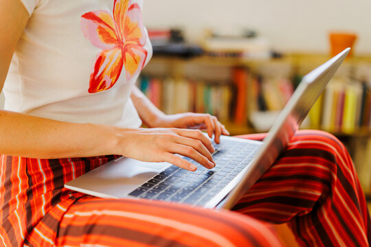 Woman typing on laptop keyboard at home