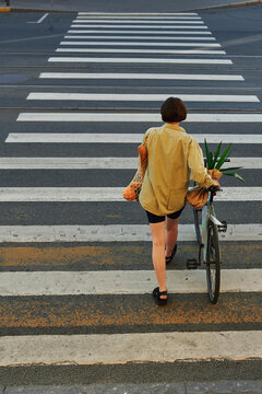 Person walks across a crosswalk carrying bicycle