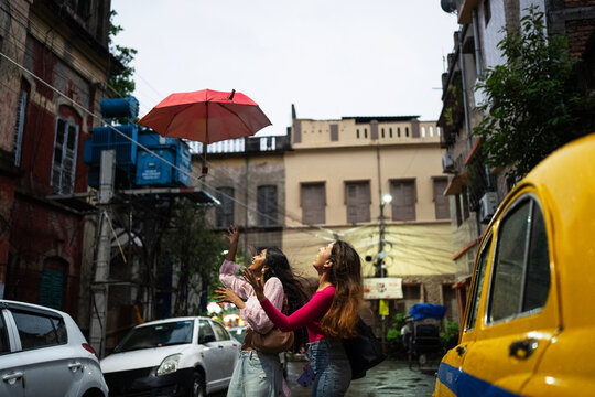 Two Young Woman throwing umbrella and making fun in a city