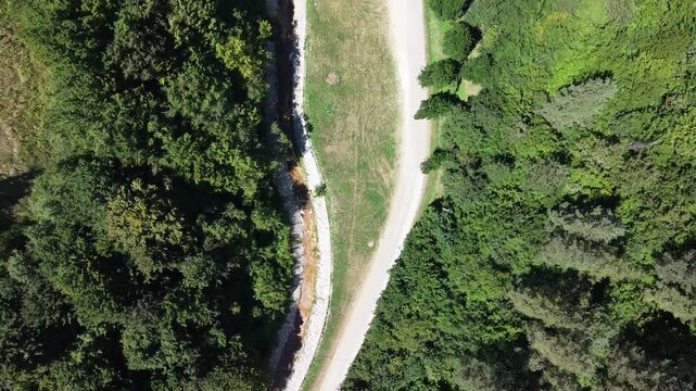 Aerial Top Down View Gravel Dirt Road Through Dense Green Forest Canopy Mountain Countryside