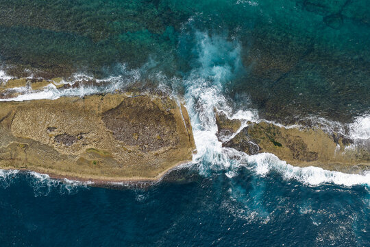 Aerial view of waves over Warden Head coastal rock shelf