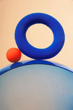 Blue torus and red sphere on curved reflective surface