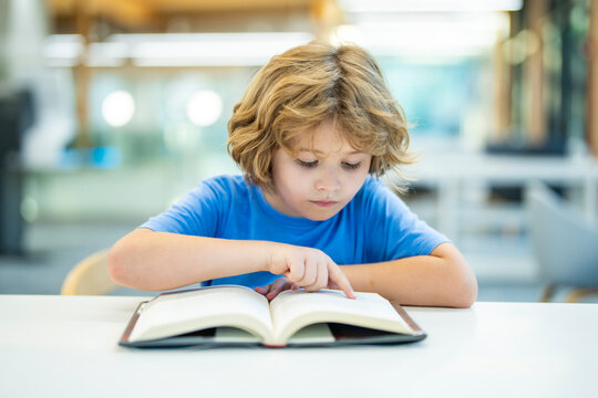 Child reading book at school library. Child student reads book. School child reads open book in library. Kid studies with books. School age child reads inside library. School reading education.