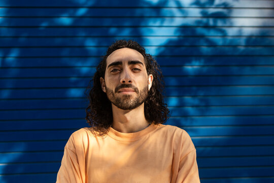 Confident man in city portrait against blue shutter wall