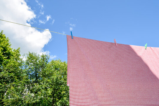 Red gingham fabric drying on clothesline under blue sky