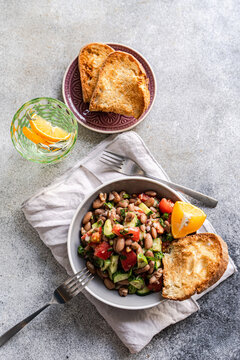 Bean and cucumber salad with toast and citrus wedges