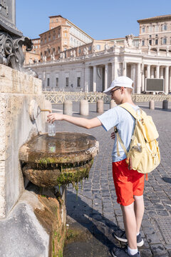 Teenager refill bottle at public fountain in Rome