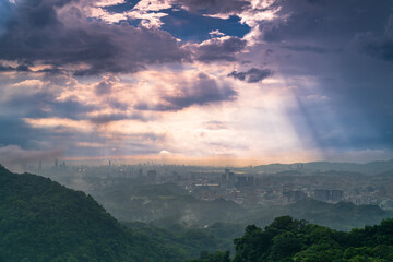 Fototapeta premium Stunning aerial view of Taipei city skyline and mountain landscape with dramatic clouds and sun rays during sunset in Taiwan.
