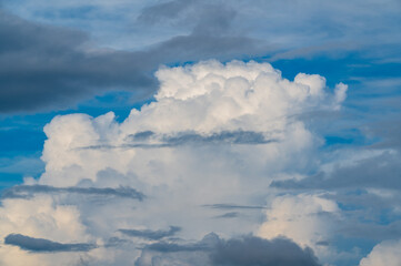 Fototapeta premium Dramatic white cumulus clouds and dark storm clouds floating across a vibrant blue sky, captured from Mount Shizitou in New Taipei City, Taiwan.