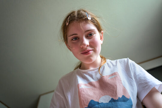 Cheerful preteen girl in low angle indoor portrait