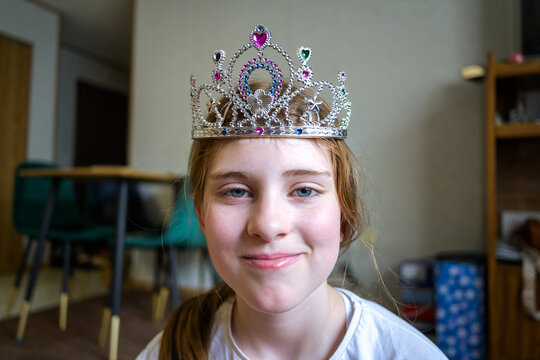 Portrait of a happy preteen girl wearing a plastic toy tiara at home