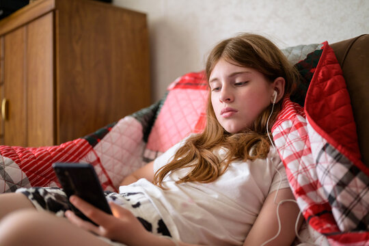 Girl relaxes on couch with smartphone and headphones