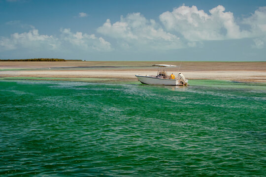 A small unmanned motor boat in tropical waters with blue sky and clouds