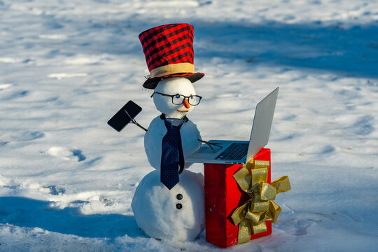 Snowman in a snowy winter field. Funny snow man with scarf and hat. Snowman for Christmas card. Winter snowman in frozen landscape.