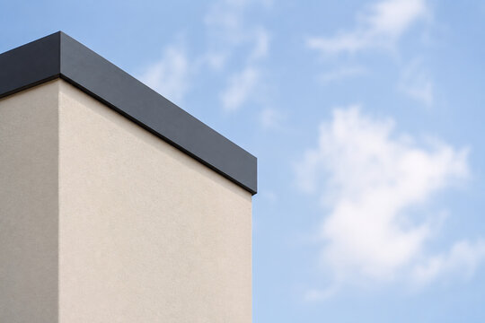 Minimalistische Flachdachfassade mit dunkler Attika vor dem Himmel