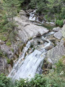 Cascading waterfall flowing through rocky mountain forest landscape