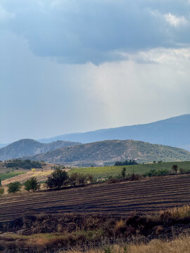 Rainy mountain countryside landscape beneath heavy storm clouds