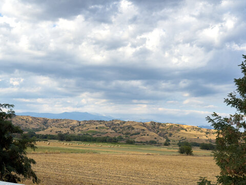Farmland hills beneath expansive dramatic cloudy countryside sky