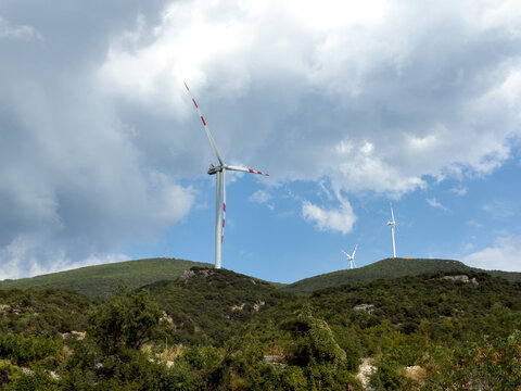 Wind Turbines On Green Mountain Beneath Dramatic Sky