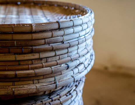 close up view of a neat stack of traditional handcrafted woven bamboo winnowing trays, showing stitched circular cane rims and rustic woven texture