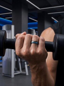 Man wearing a smart ring while lifting a dumbbell in a gym