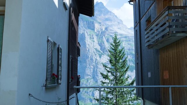 Majestic alpine mountain peak appearing between two traditional swiss chalets in a village. Switzerland