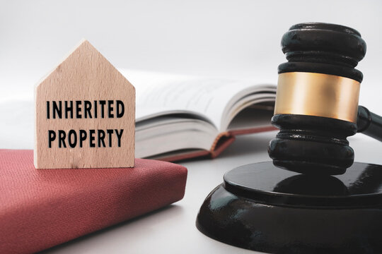 Judge gavel with Inherited property text on wooden house on white background. Inheritance Law Concept.