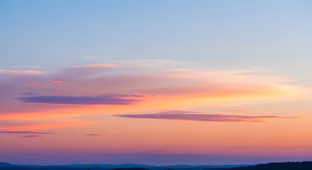 Fototapeta premium Serene sunset sky with soft pink and orange clouds over a distant hazy landscape