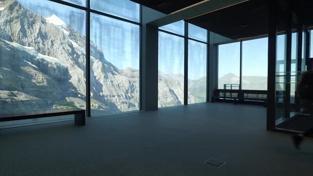 Silhouette of a man walking inside a panoramic building with stunning views of the eiger express station. Switzerland